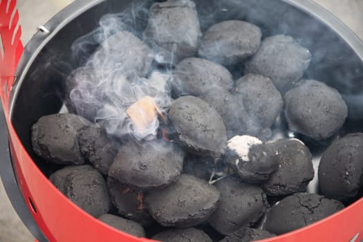 a man lights a fire with a lighter special charcoals for a barbecue a barbecue house on the terrace prepares a place for a barbecue. High quality photo