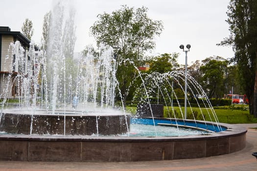 Photo of working fountain in park during day. Drops, water pressure. Fountain jets.