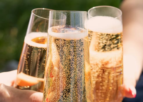 women drinking wine. three glasses white wine in female hands. flute glass of champagne with bubbles outdoors isolated against. garden scene blurred in the background. Cold Beer in glass. outdoor