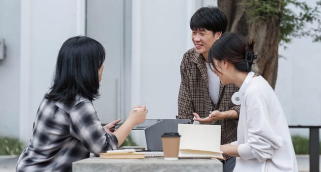 Group of Student working on laptop and record in book together at university. Happy friend successfully completes the thesis report and passed the final exam in asian college...