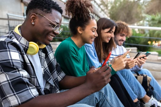 Group of happy multiracial teenage college friend students ignoring each other looking at mobile phone. Smartphone addiction. Youth lifestyle and social media concept.