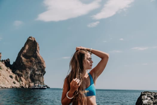 Woman travel sea. Young Happy woman in a long red dress posing on a beach near the sea on background of volcanic rocks, like in Iceland, sharing travel adventure journey