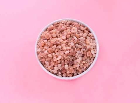 Flatly Pink Himalayan Rock Salt, Halite In White Ceramic Bowl On Pink Background. Top View Horizontal Plane, Copy Space For Text. High quality photo.