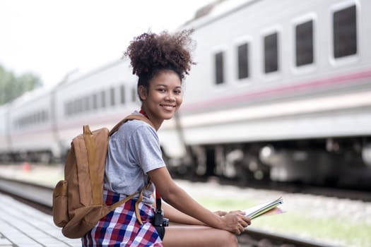 Young woman female smiling traveler with back pack looking to map while waiting for the train at train station. High quality photo