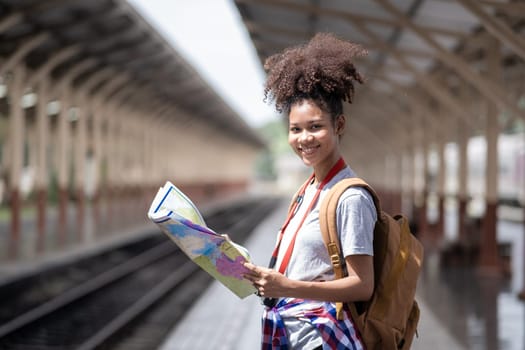 Young woman female smiling traveler with back pack looking to map while waiting for the train at train station. High quality photo