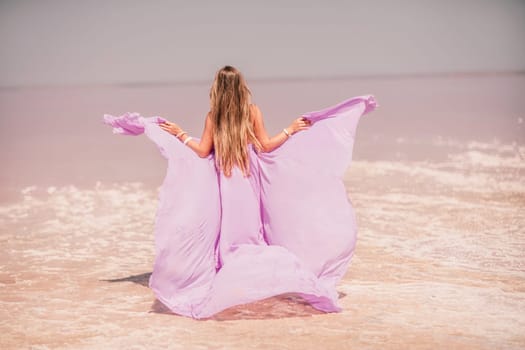 Woman pink salt lake. Against the backdrop of a pink salt lake, a woman in a long pink dress takes a leisurely stroll along the white, salty shore, capturing a wanderlust moment