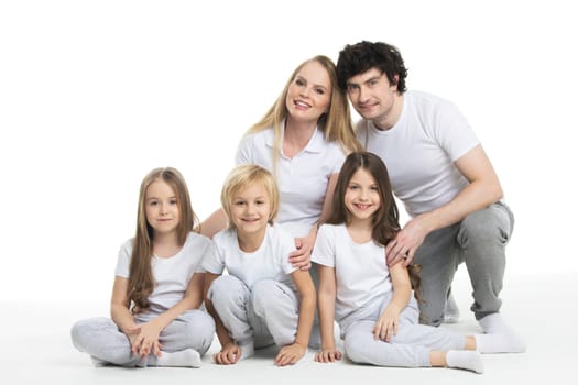 Studio portrait of family in white clothes with three children isolated on white background