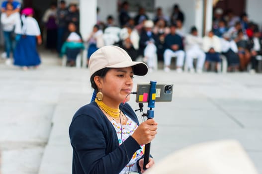 Otavalo, Ecuador - 24 de junio de 2023: indigenous reporter doing a live in the inti raymi of otavalo. High quality photo