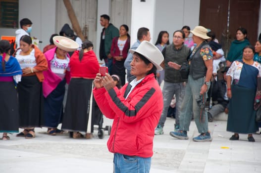 Otavalo, Ecuador - 24 de junio de 2023: indigenous man with a cell phone recording in the inti raymi surrounded by people from otavalo and cayambe. High quality photo