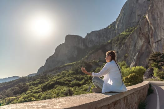 Profile of a woman doing yoga in the top of a cliff in the mountain. Woman meditates in yoga asana Padmasana.