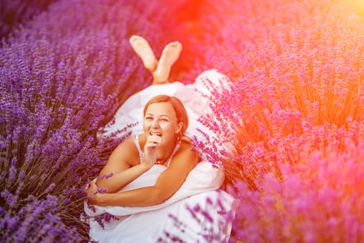 Woman lavender field. A middle-aged woman lies in a lavender field and enjoys aromatherapy. Aromatherapy concept, lavender oil, photo session in lavender.