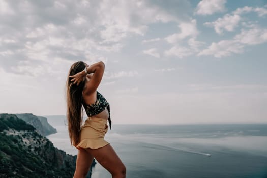 Woman travel sea. Happy tourist taking picture outdoors for memories. Woman traveler looks at the edge of the cliff on the sea bay of mountains, sharing travel adventure journey.