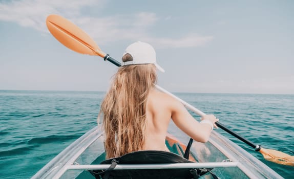 Woman in kayak back view. Happy young woman with long hair floating in transparent kayak on the crystal clear sea. Summer holiday vacation and cheerful female people having fun on the boat.