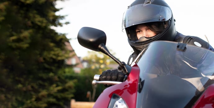 a young girl biker in a helmet and a moto suit riding a red motorcycle on a trip ,High quality photo