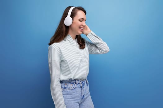 optimist energetic brunette young lady with hair below her shoulders listens to music with headphones.
