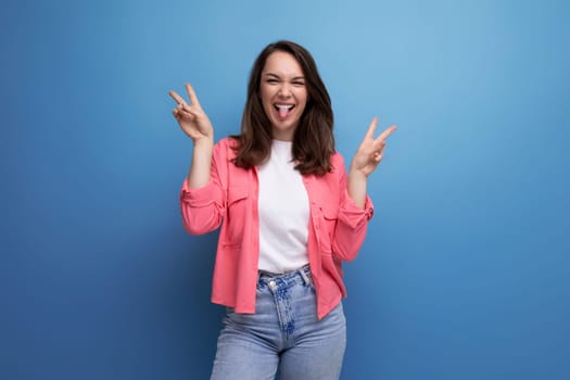 positive brunette young woman in pink shirt and jeans on studio isolated background.