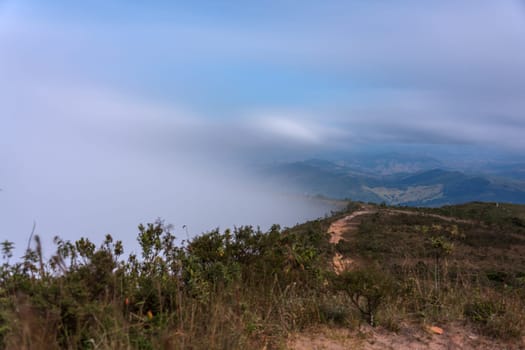A winding mountain road covered in mist and fog with a beautiful view of the surrounding landscape. Perfect for nature or outdoor-themed designs.