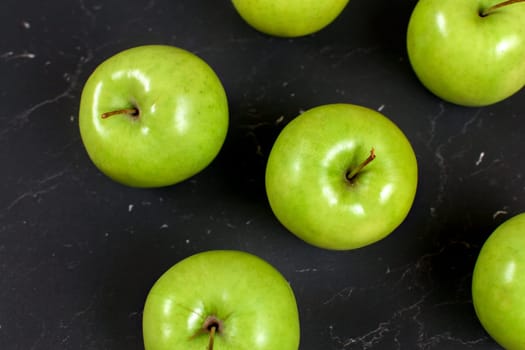 Top down view, detail of green apples on black marble board.