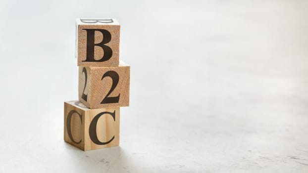 Pile with three wooden cubes - letters B2C meaning Business to customer on them, space for more text / images at right side.