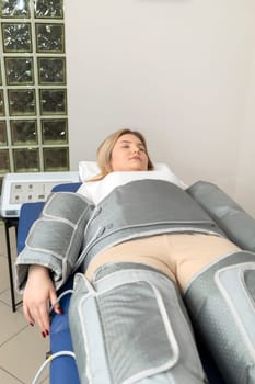 Pressure therapy procedure. Woman lying in massaging suit in spa clinic, treatment of varicose veins, edema, lymphatic drainage, weight loss. Relaxation,cure. Pressotherapy machine. Vertical