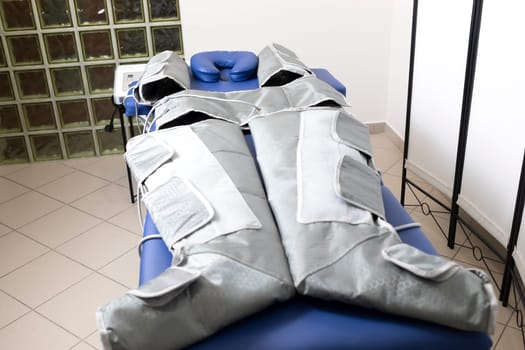 Pressure therapy gray massaging suit on blue couch in spa, treatment of varicose veins, edema, lymphatic drainage, weight loss. Empty pressotherapy machine,device. No people. Horizontal,copyspace
