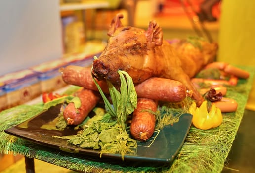 Grilled whole pig ready to serve. Sausage and a young pig on a platter.