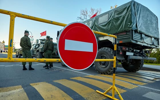 Soldiers stand near the car against the background of the STOP sign. The Belarusian military is conducting exercises.