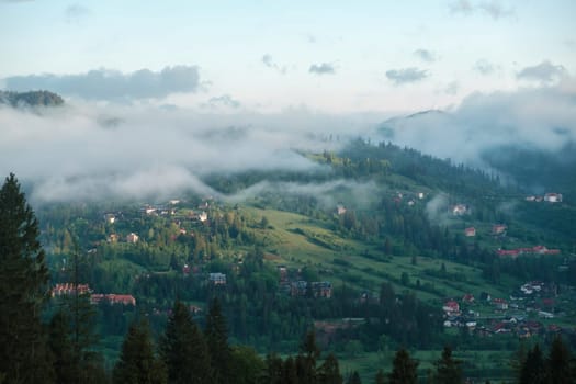 mountainous rural landscape at sunset. beautiful scenery with forests, hills and meadows in evening light. ridge with high peak in the distance. village in the distant valley download photo