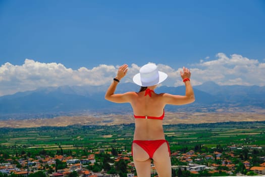 Happy woman enjoying vocation, joyful in summer beautiful view. Beautiful bikini model happy on travel wearing beach sun hat in Turkey, download photo