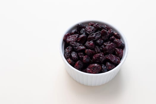 Superfood Heap Of Dried Cranberries In White Bowl On Beige Background. Selective Focus. Sweet Dehydrated Cranberries. Nutrients And Vitamins. Horizontal And Copy Space. High quality photo