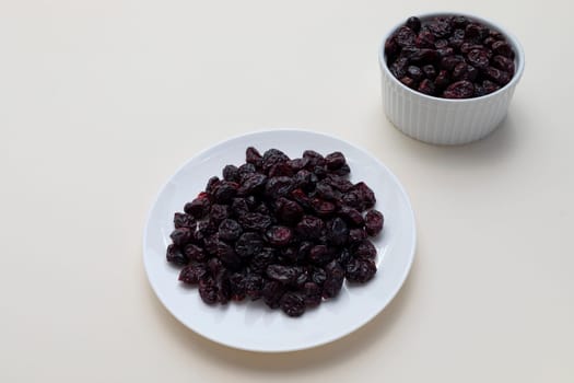 Dried Cranberries On White Plate On Beige Background. Superfood. Selective Focus. Sweet Dehydrated Cranberries. Nutrients And Vitamins. Horizontal Plane. High quality photo