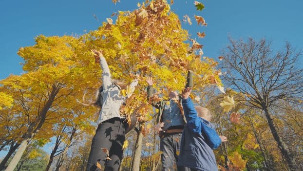 A happy family in an autumn park having fun and crumbling leaves