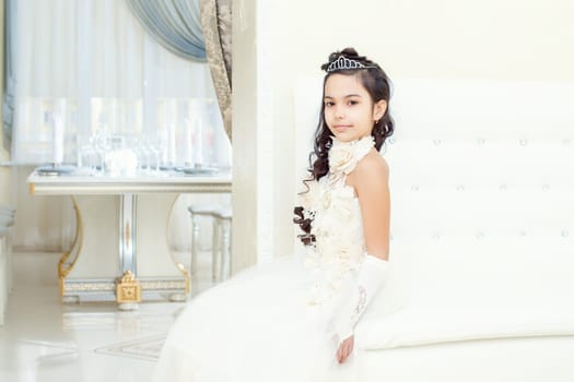 Image of lovely little girl posing in white luxurious dress