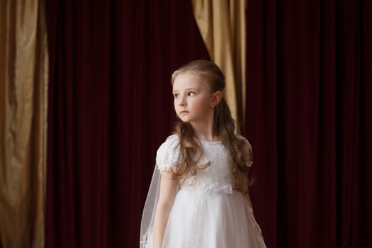 Girlie in smart white dress posing on curtain backdrop