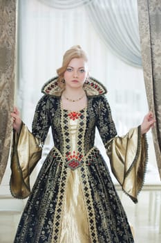 Image of unsmiling young woman posing in luxurious royal dress