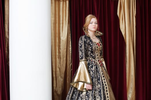 Actress posing in historical costume on curtain backdrop