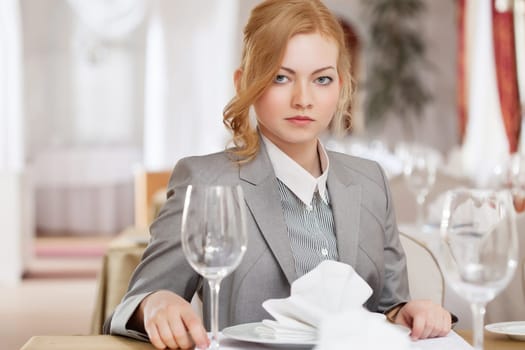 Serious red-haired business woman posing at table, close-up
