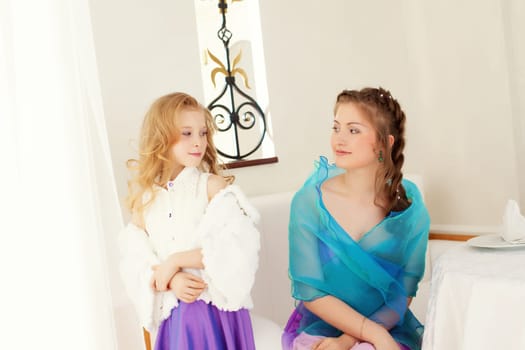 Image of playful well-dressed sisters looking at each other