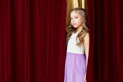 Pretty blonde girl posing looking out curtain, close-up