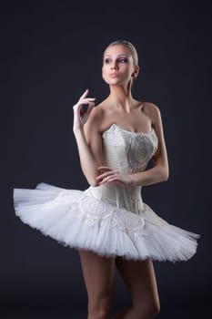 Portrait of cute young blonde posing in tutu, on gray background