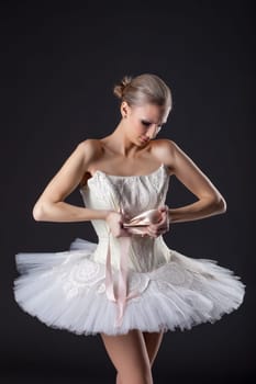 Concentrated pretty ballet dancer kneads pointe in studio
