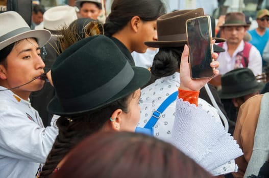 Otavalo, Ecuador - 24 de junio de 2023: indigenous woman recording with a cell phone the festival of inti raymi in otavalo ecuador. High quality photo