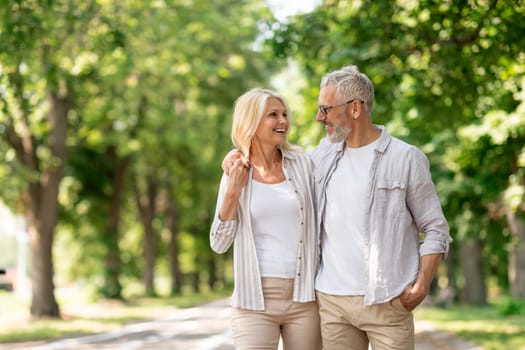 Romantic Senior Couple Walking Outdoors In Summer Park And Embracing, Loving Happy Mature Spouses Hugging And Smiling To Each Other, Cheerful Husband And Wife Enjoying Outside Walk, Copy Space