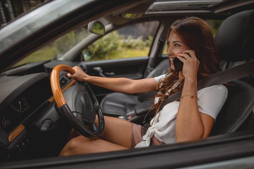 Woman holding smartphone in her hand and talking while driving a car.