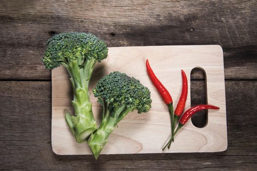 Fresh broccoli and chilli on wood table background. top view