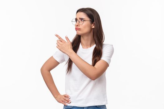 Waist-up portrait of pity or jealous young brunette female student missed great opportunity, feel regret and uneasy emotion, sulking grieving pointing and looking upper left corner.