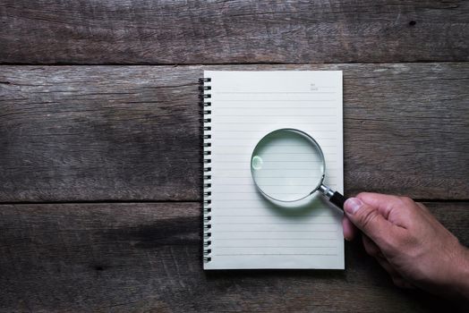 note book and Magnifier on wood table