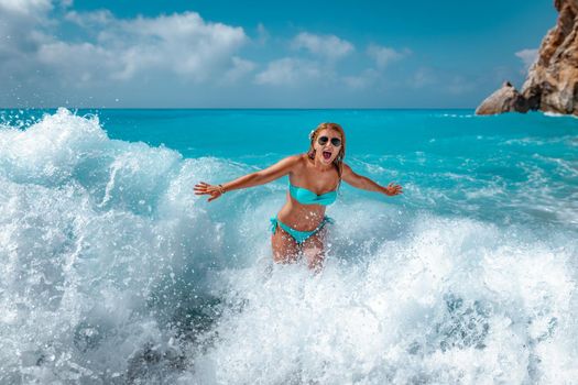 A young woman having fun in the waves of the sea which are splashing her.
