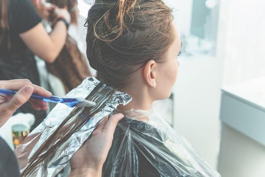 woman having hair foiled while coloring in a hair salon