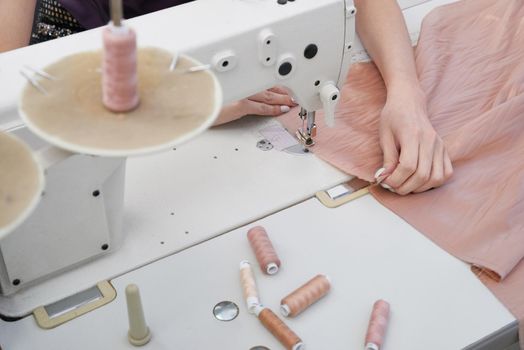 Woman using sewing machine in tailor studio or modern atelier shop